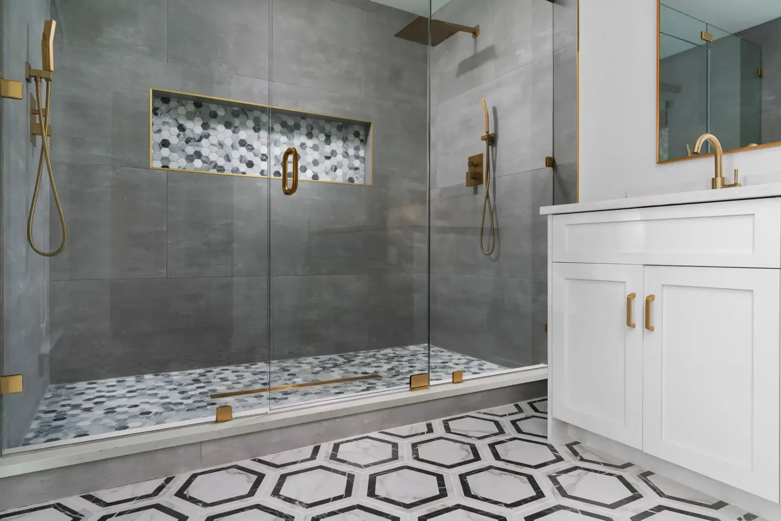Walk-in shower in large-format grey tile with a full-width niche and hexagon mosaic floor &mdash; Emerald Forest remodel in Austin by Bailey & Bear Construction
