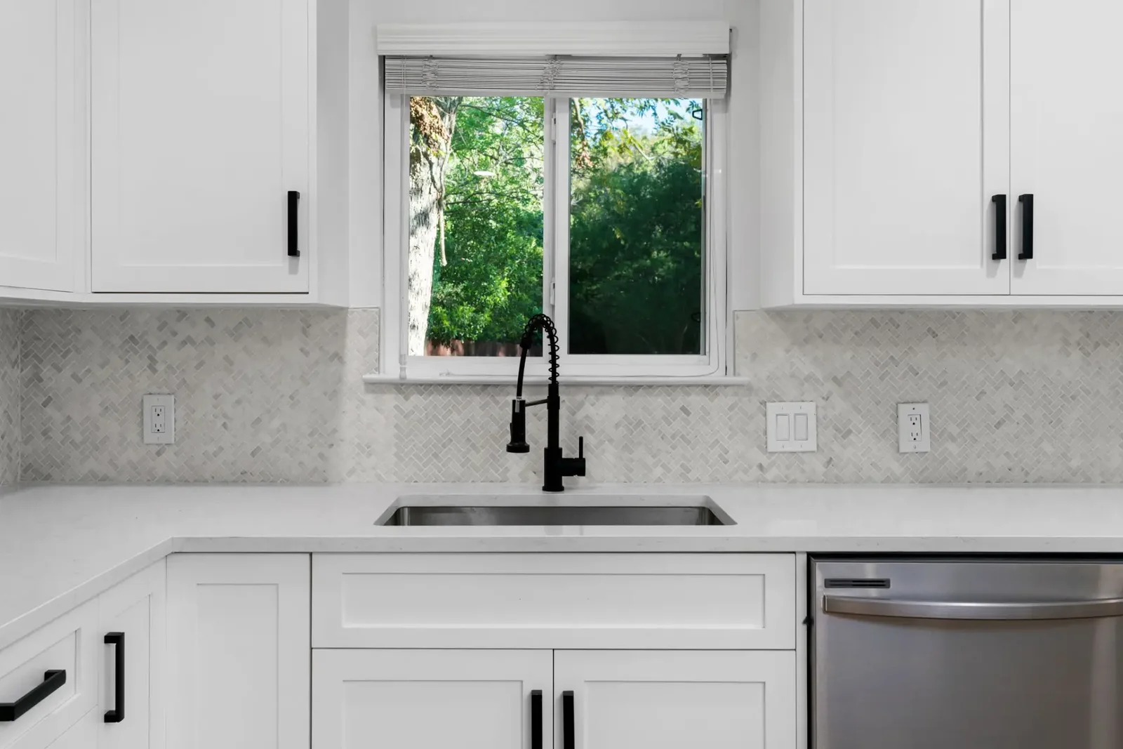Kitchen sink run with herringbone tile backsplash, quartz counter and matte black faucet &mdash; Emerald Forest remodel in Austin by Bailey & Bear Construction