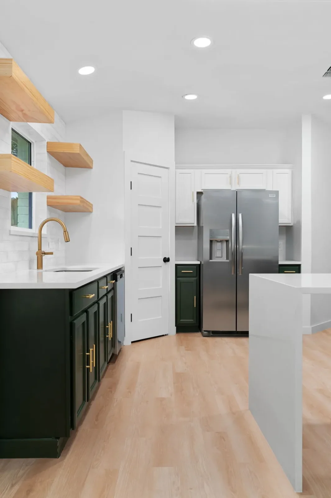 Green-and-white kitchen with open shelving looking through to the living area after a wall removal &mdash; Bremner remodel in Austin by Bailey & Bear Construction