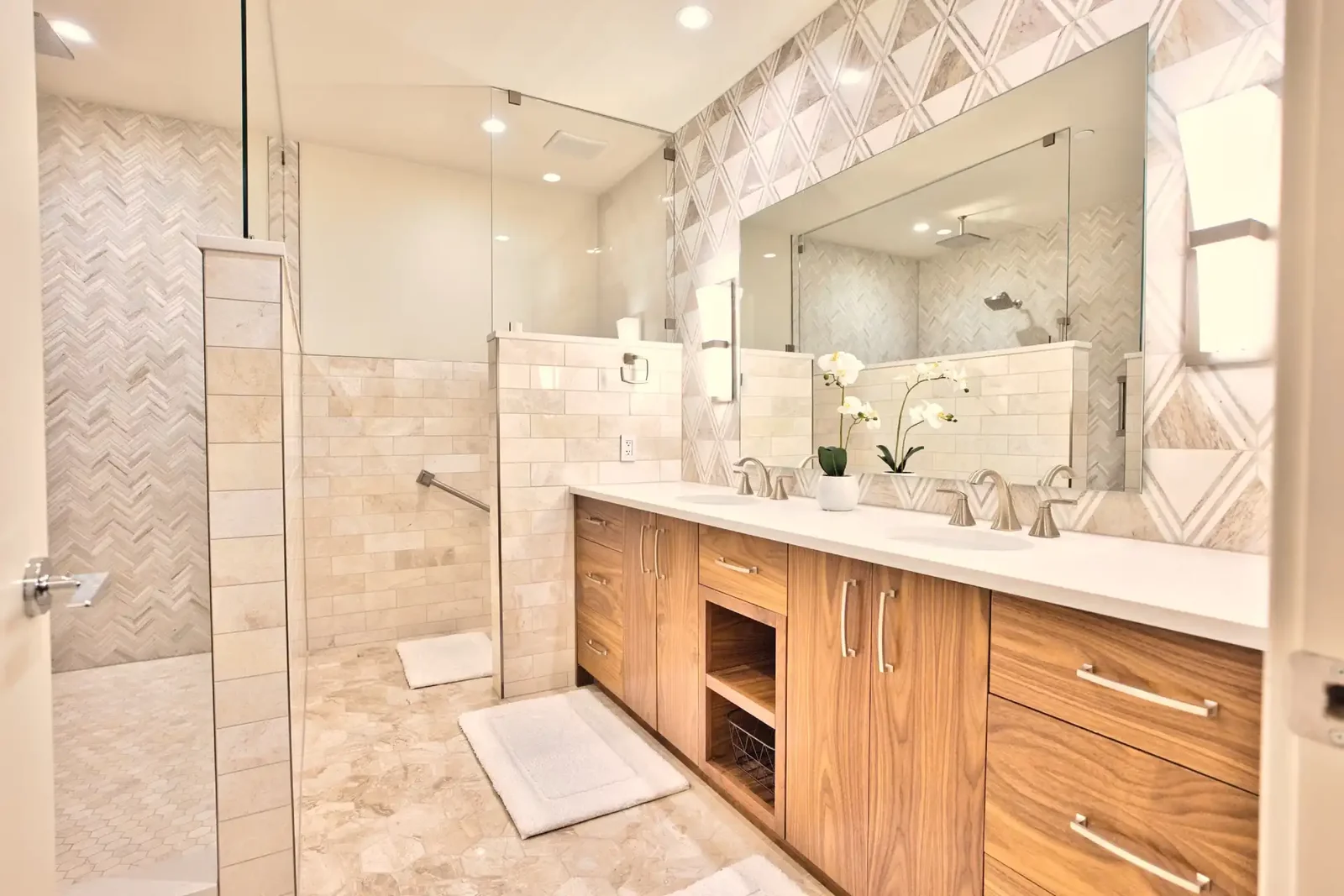 Primary bathroom with a long walnut double vanity, quartz top and a glass walk-in shower in stone tile &mdash; East Avenue remodel in Austin by Bailey & Bear Construction