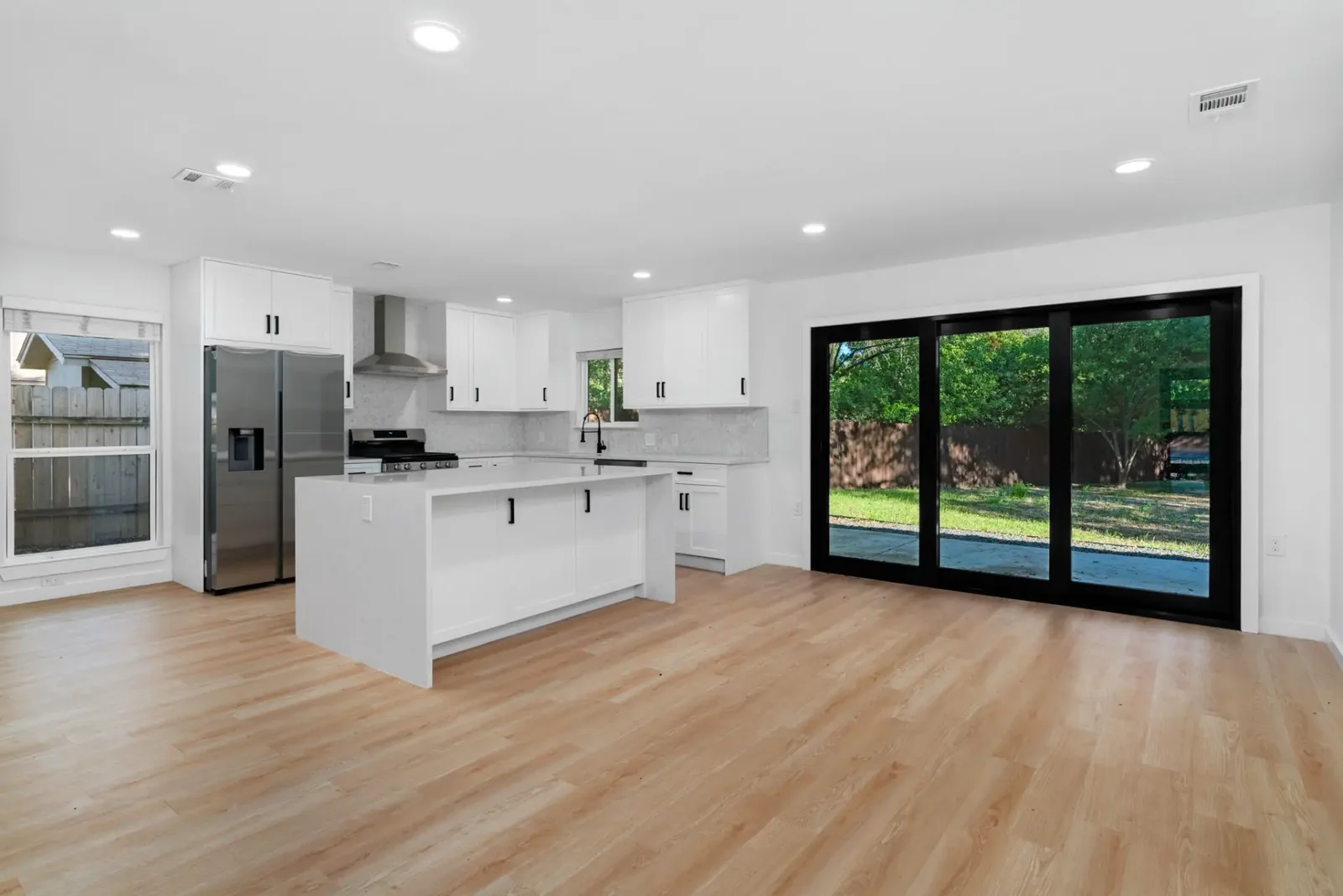 Open-plan living, dining and kitchen space created by removing a wall during a full home renovation &mdash; Emerald Forest project in Austin by Bailey & Bear Construction